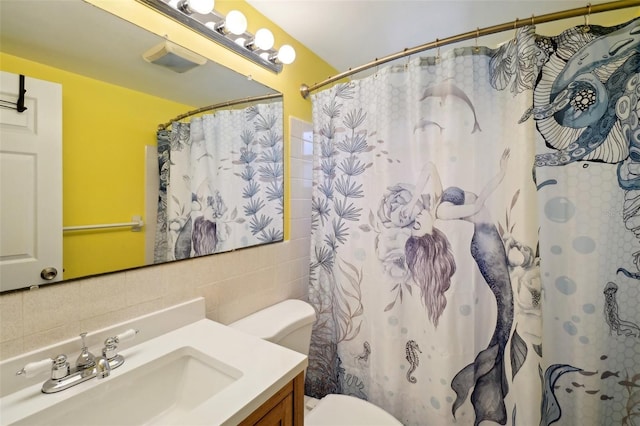 bathroom featuring a shower with shower curtain, backsplash, vanity, tile walls, and toilet