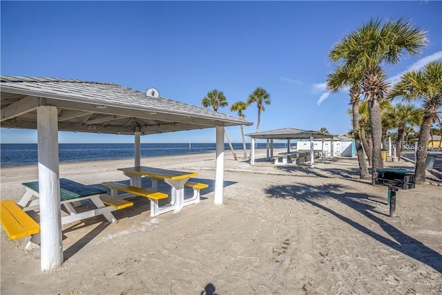 view of home's community with a gazebo, a water view, and a beach view