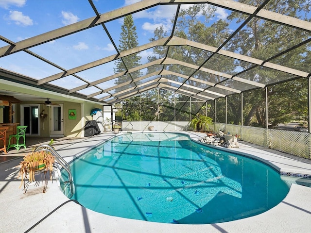 view of pool with ceiling fan, a patio area, a lanai, and an outdoor bar