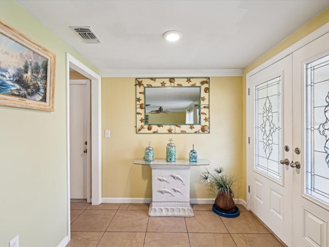 entryway with light tile patterned floors and crown molding