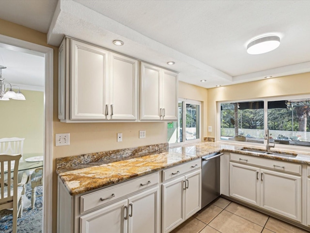 kitchen with light stone countertops, white cabinetry, stainless steel dishwasher, and sink