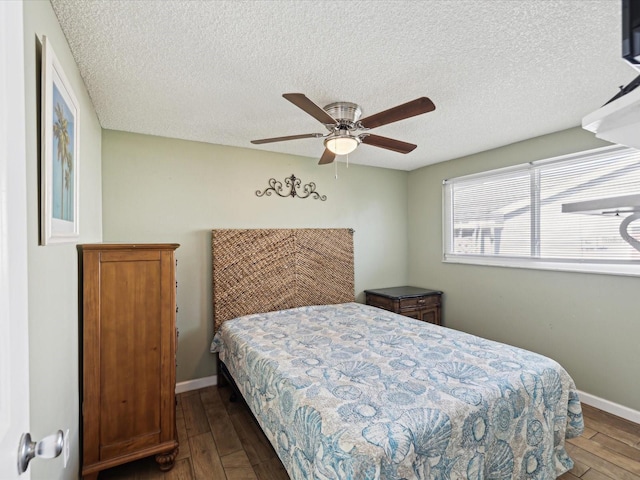 bedroom featuring ceiling fan, dark hardwood / wood-style flooring, and a textured ceiling