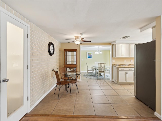 dining room with ceiling fan, light tile patterned floors, and brick wall