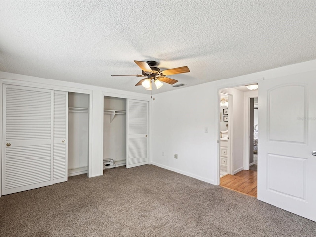 unfurnished bedroom with ensuite bathroom, ceiling fan, a textured ceiling, light colored carpet, and multiple closets