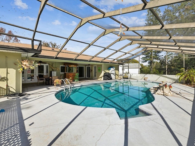 view of swimming pool featuring glass enclosure, ceiling fan, and a patio area