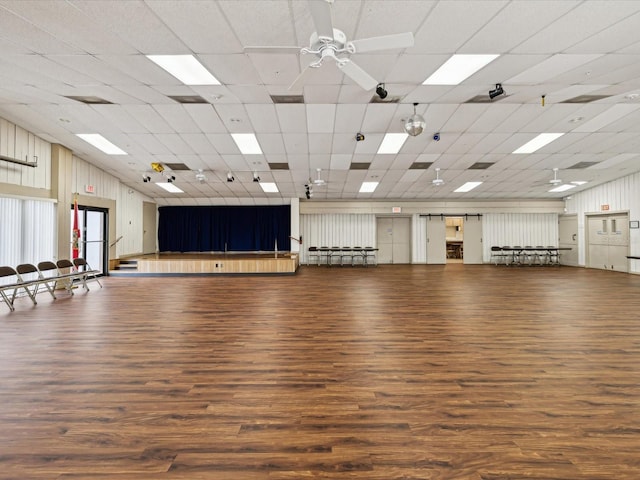 interior space with ceiling fan, a drop ceiling, and dark wood-type flooring