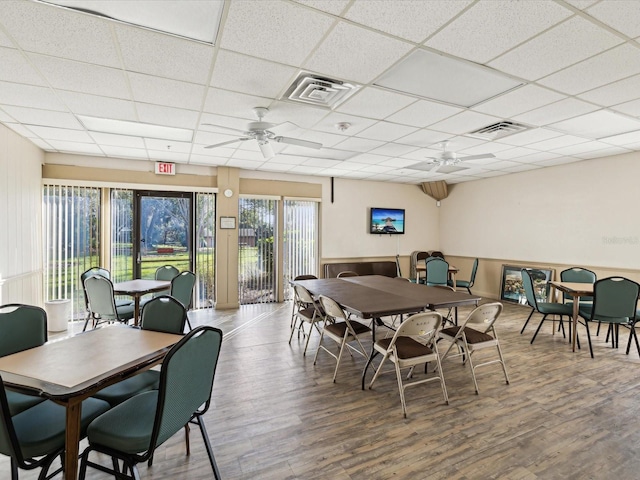 dining space featuring hardwood / wood-style flooring, ceiling fan, and a drop ceiling