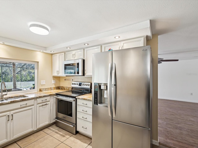 kitchen featuring ceiling fan, white cabinetry, sink, light tile patterned floors, and appliances with stainless steel finishes