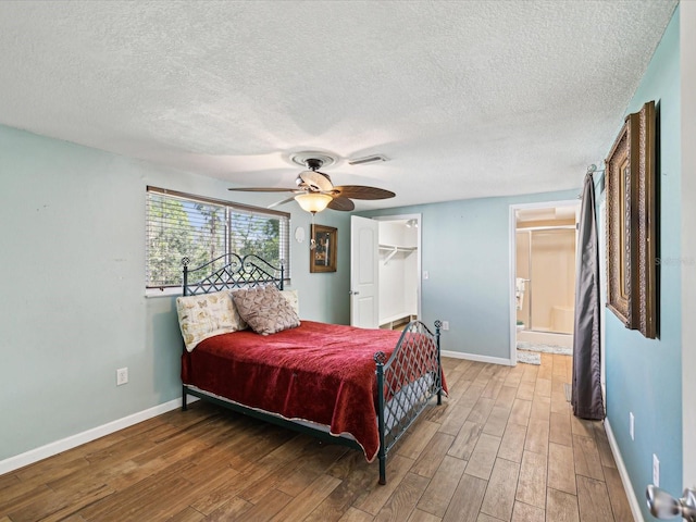 bedroom featuring wood-type flooring, a closet, a spacious closet, and ceiling fan