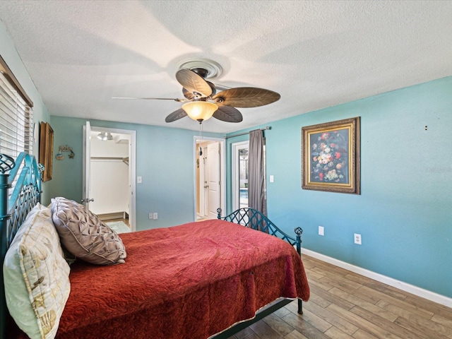 bedroom with ceiling fan, a spacious closet, hardwood / wood-style floors, a textured ceiling, and a closet