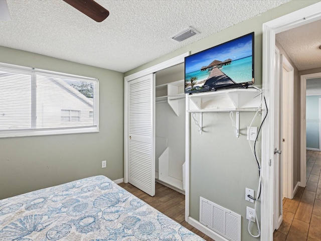 bedroom with hardwood / wood-style floors, ceiling fan, and a textured ceiling