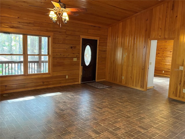 foyer entrance with wooden walls, ceiling fan, and wooden ceiling