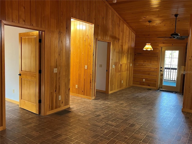 empty room with wood walls, ceiling fan, wooden ceiling, and lofted ceiling