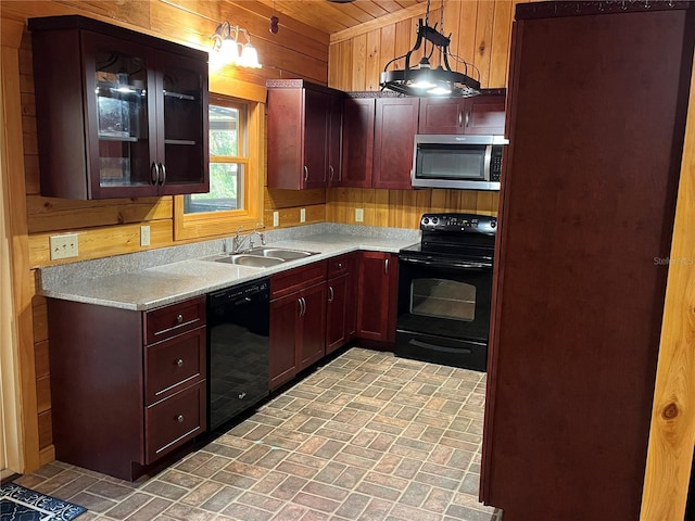 kitchen featuring sink, hanging light fixtures, wood walls, and black appliances