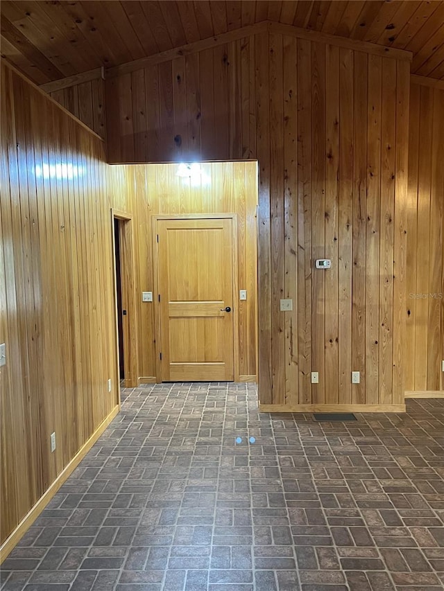 hallway with wooden walls, wooden ceiling, and vaulted ceiling