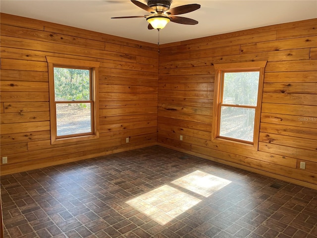 spare room with plenty of natural light, wood walls, and ceiling fan