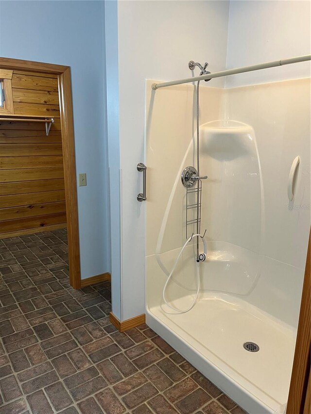 bathroom featuring a shower and wood walls