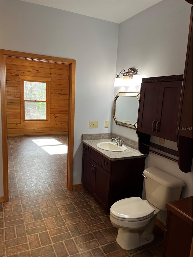 bathroom featuring vanity, toilet, and wooden walls