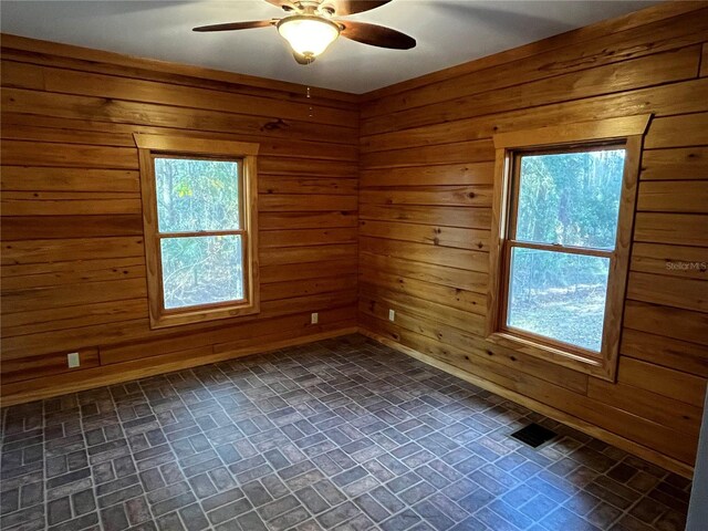 spare room with ceiling fan and wood walls