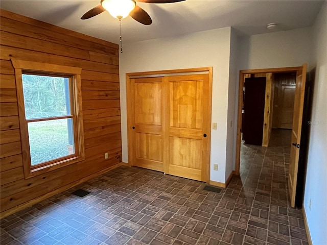 unfurnished bedroom featuring ceiling fan and wooden walls