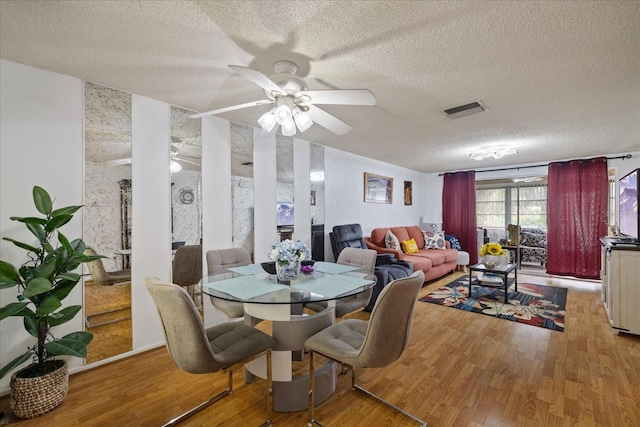 dining area with a textured ceiling, ceiling fan, and hardwood / wood-style flooring