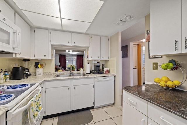 kitchen featuring white appliances, decorative backsplash, white cabinetry, light tile patterned flooring, and sink