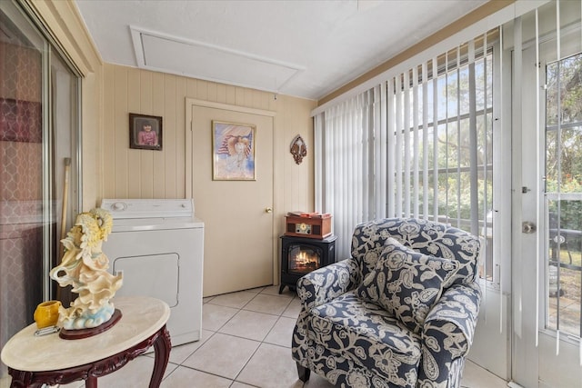 living area featuring washer / clothes dryer, wooden walls, a wealth of natural light, and light tile patterned floors