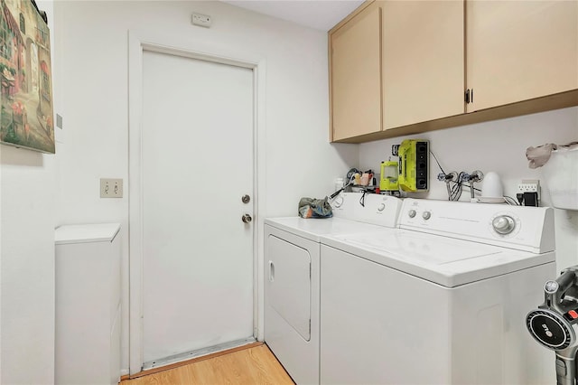 laundry room with cabinets, light wood-type flooring, and washing machine and clothes dryer