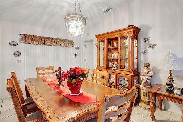 dining area with a notable chandelier, light tile patterned flooring, and vaulted ceiling