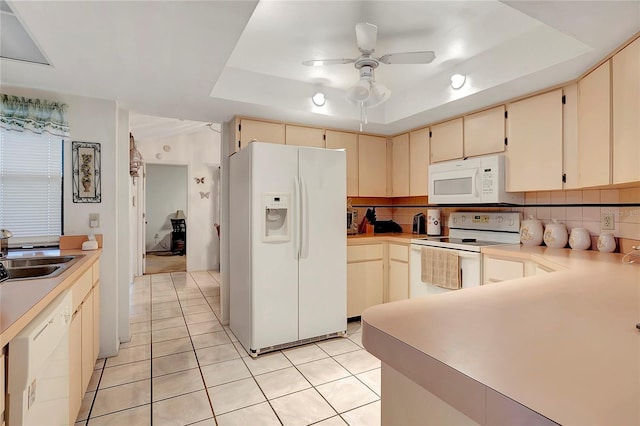 kitchen with sink, white appliances, cream cabinets, and a tray ceiling