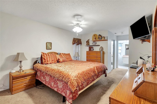 bedroom featuring ensuite bathroom, ceiling fan, light colored carpet, and a textured ceiling