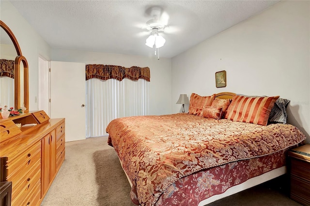 bedroom featuring a textured ceiling, ceiling fan, and light carpet