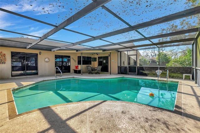 view of pool featuring glass enclosure, ceiling fan, and a patio area