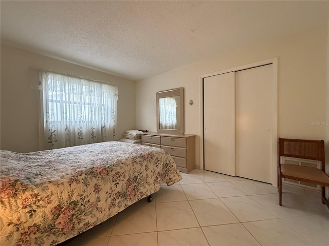 bedroom with a closet, light tile patterned floors, and a textured ceiling