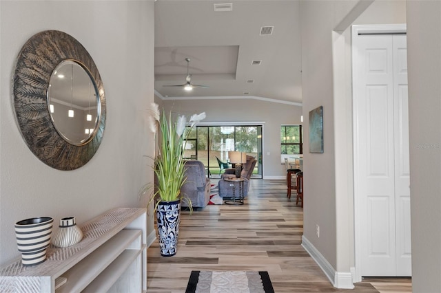 foyer with light hardwood / wood-style floors, vaulted ceiling, ceiling fan, and crown molding