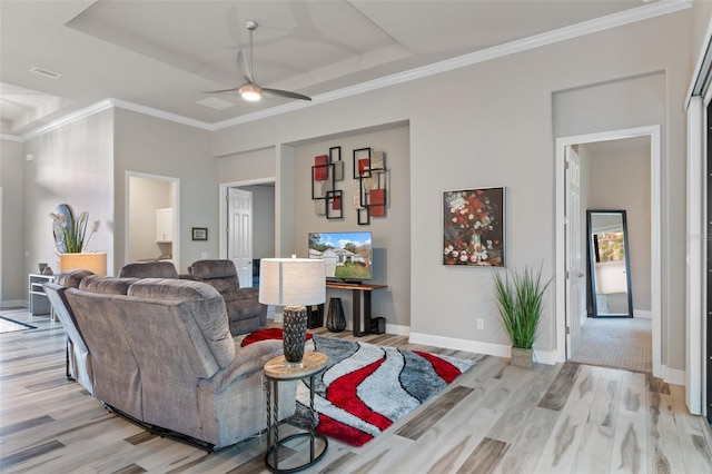 living room with a tray ceiling, ceiling fan, light hardwood / wood-style flooring, and ornamental molding