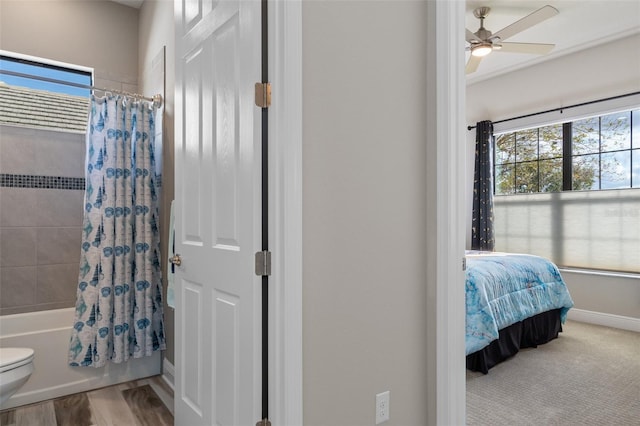 bathroom with hardwood / wood-style floors, ceiling fan, and shower / bathtub combination with curtain