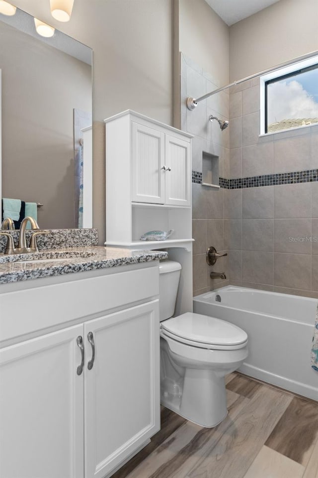 full bathroom with hardwood / wood-style floors, vanity, toilet, and tiled shower / bath combo