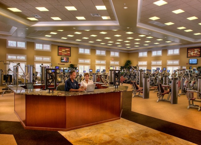 gym with carpet flooring, ornamental molding, and a high ceiling