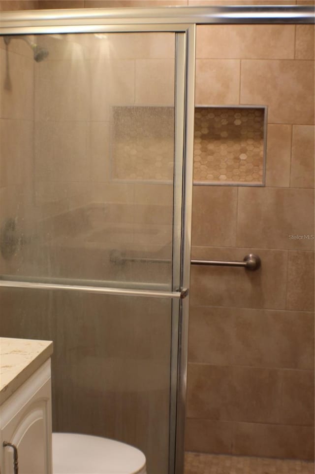 bathroom featuring vanity, toilet, and a shower with shower door