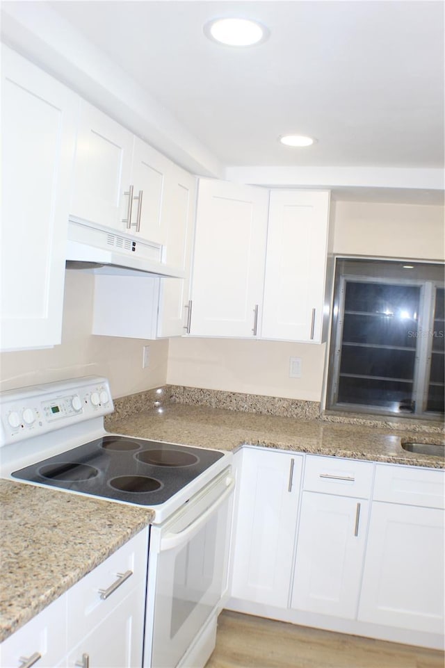 kitchen with white cabinetry, sink, light stone counters, white electric stove, and light hardwood / wood-style floors