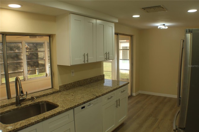 kitchen featuring dishwasher, stone countertops, white cabinets, and sink