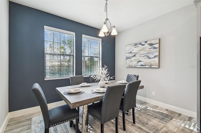 dining room with light wood-type flooring and an inviting chandelier