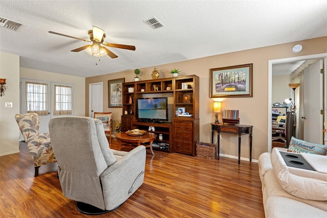 living room with a textured ceiling, hardwood / wood-style flooring, and ceiling fan