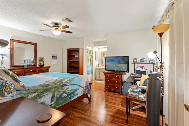 bedroom featuring ceiling fan, wood-type flooring, a textured ceiling, and ensuite bath