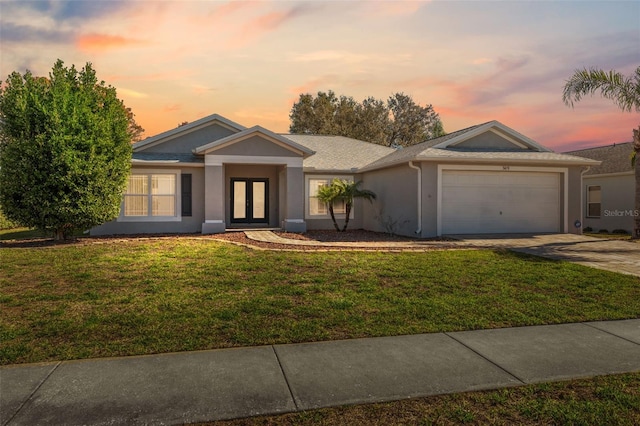 ranch-style home featuring a lawn, french doors, and a garage