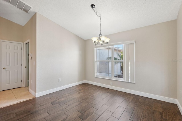 spare room featuring a textured ceiling and an inviting chandelier