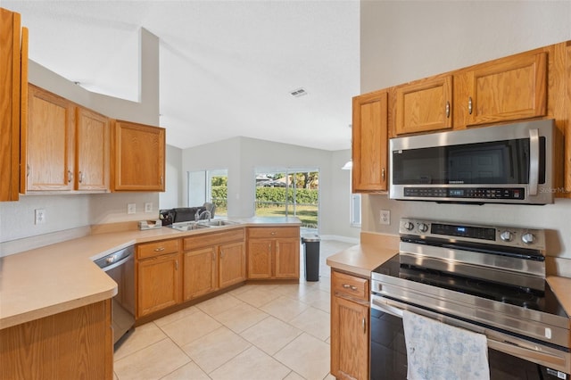 kitchen with sink, kitchen peninsula, lofted ceiling, light tile patterned floors, and appliances with stainless steel finishes