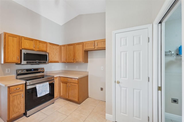 kitchen with light tile patterned flooring, stainless steel appliances, and high vaulted ceiling