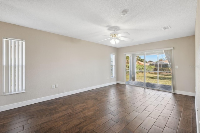 empty room with a textured ceiling, dark hardwood / wood-style flooring, and ceiling fan